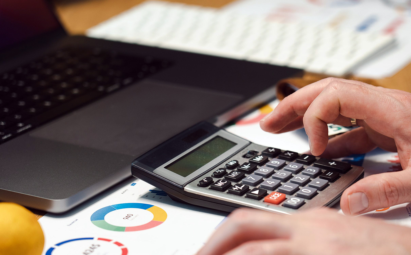 Dirigeant calculant un décalage de trésorerie avec calculatrice, ordinateur portable et graphiques financiers